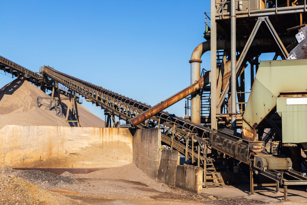 Close up detail part of heavy metal construction of open pit gravel plant sand quarry big rusty rotor machine material excavating and crushing. Industrial machinery factory equipment steel background
